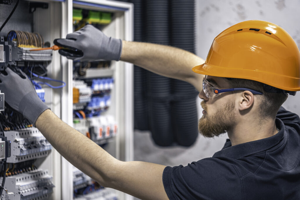 male electrician working in a switchboard with fuses.